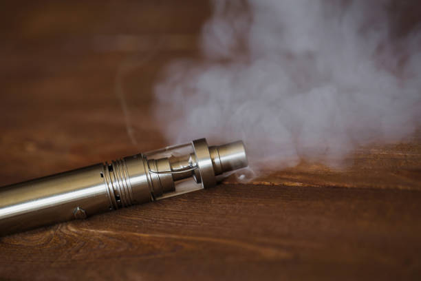 Electronic cigarette on a wooden table. Smoke