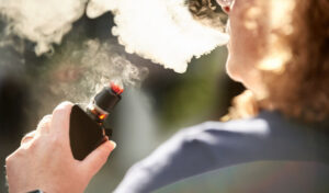 Over the shoulder view of a woman smoking electronic cigarette outdoors